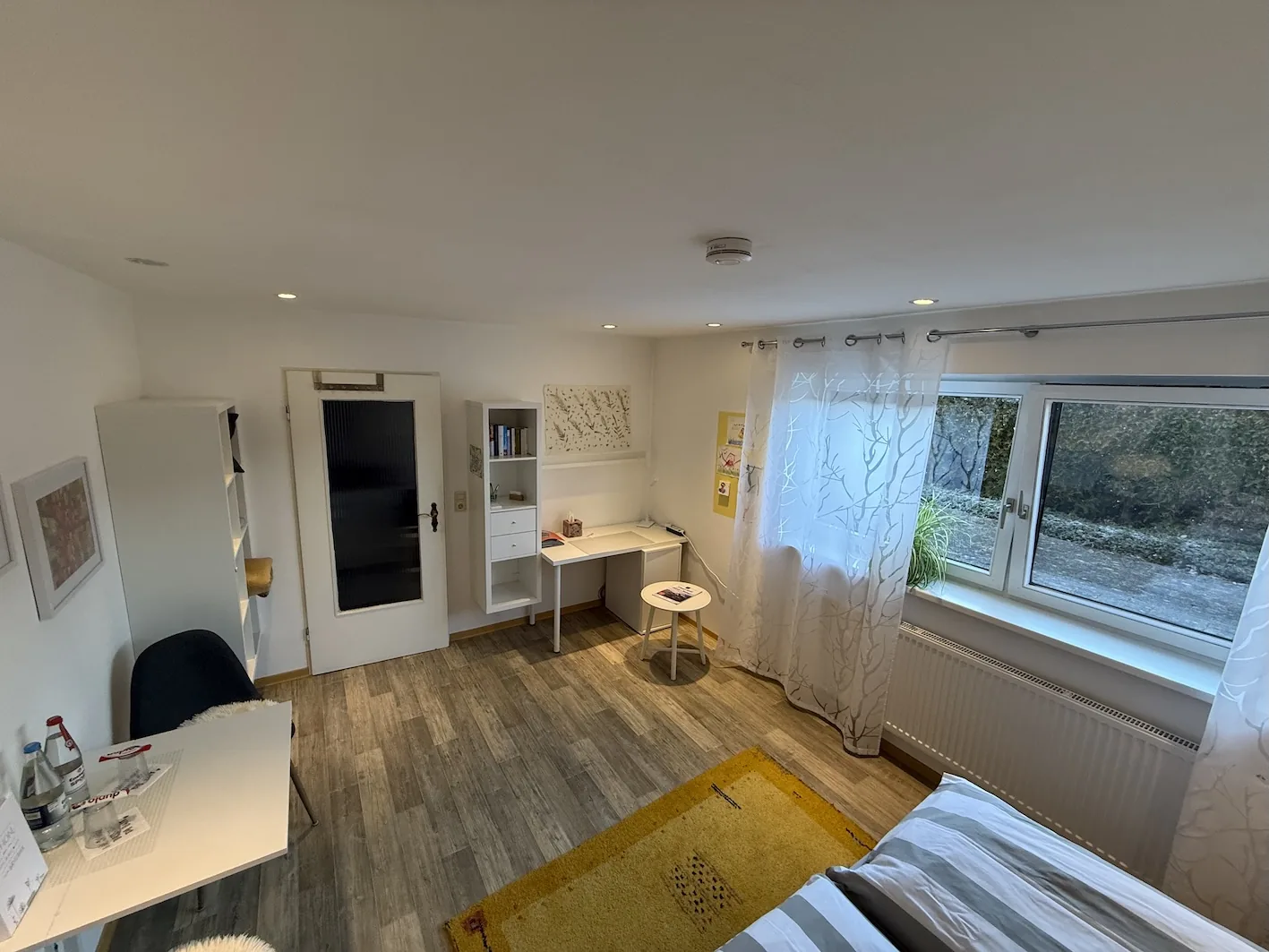 Schlafzimmer mit Schreibtisch und Blick aus dem Fenster